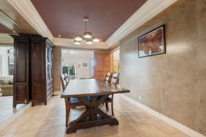 Dining space featuring crown molding, baseboards, light tile patterned flooring, and a chandelier
