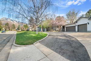 View of front of house featuring a mountain view, a front lawn, an attached garage, and aphalt driveway