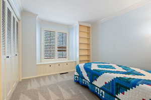 Bedroom featuring visible vents, a closet, ornamental molding, and carpet floors