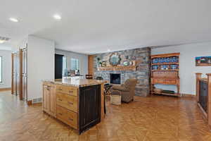 Kitchen with visible vents, a center island, light stone counters, and a textured ceiling