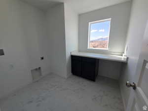 Laundry area with marble finish floor, hookup for an electric dryer, and cabinet space