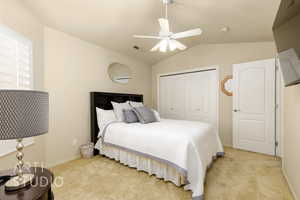 Bedroom featuring a closet, light carpet, vaulted ceiling, and ceiling fan