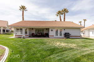 Back of house featuring french doors, a yard, stucco siding, a tiled roof, and a patio area