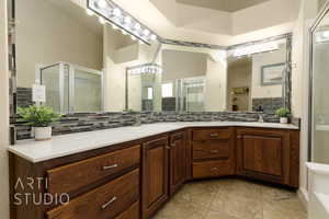 Full bath with decorative backsplash, a stall shower, and vanity