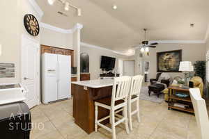 Kitchen with white fridge with ice dispenser, ornamental molding, a ceiling fan, open floor plan, and light countertops