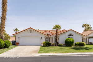 Mediterranean / spanish-style home with stucco siding, a garage, concrete driveway, a tile roof, and a front lawn