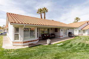 Back of property featuring a tile roof, a yard, a patio, and stucco siding