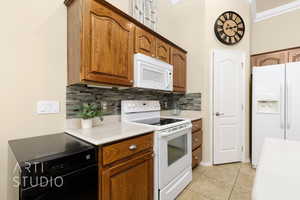 Kitchen with white appliances, decorative backsplash, light countertops, and light tile patterned flooring