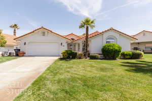 Mediterranean / spanish home featuring a tiled roof, stucco siding, a front lawn, concrete driveway, and an attached garage
