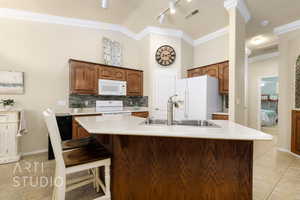 Kitchen featuring white appliances, ornamental molding, light countertops, light tile patterned floors, and decorative backsplash