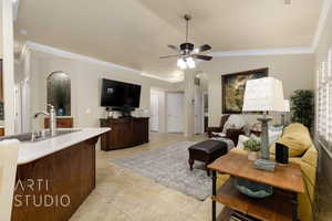Living area with a ceiling fan, crown molding, and arched walkways