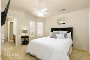 Bedroom featuring light carpet, vaulted ceiling, ensuite bath, and ceiling fan