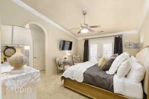 Bedroom with ornamental molding, light colored carpet, arched walkways, ceiling fan, and access to exterior