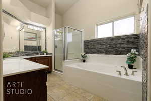 Full bathroom with vanity, a shower stall, a garden tub, backsplash, and stone tile floors