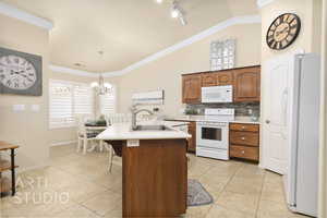 Kitchen with white appliances, light countertops, a chandelier, lofted ceiling, and a kitchen island with sink