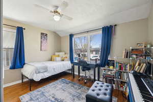 Bedroom with lofted ceiling, baseboards, and wood finished floors, a closet and wardrobe