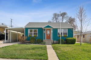 Bungalow-style home featuring an attached carport, a front yard, roof with shingles, and driveway