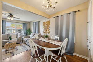 Dining space with a textured ceiling, wood finished floors, ceiling fan with a chandelier