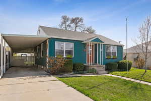 View of front of house with a shingled roof, an attached carport, a front lawn, a gate, and driveway
