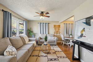 Living room featuring ceiling fan, baseboards, wood finished floors, and a textured ceiling