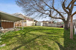 View of yard with a storage shed, a fenced backyard, a mountain view, and covered patio