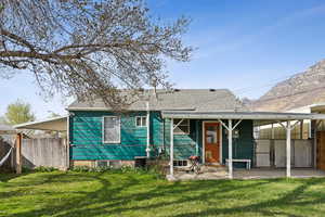 Rear view of house with a yard, a shingled roof, fence, and covered patio area