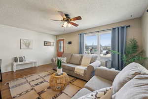 Living area featuring  a ceiling fan, wood finished floors, and a textured ceiling