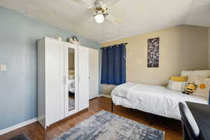 Bedroom with baseboards, a ceiling fan, wood finished floors, and lofted ceiling,a closet and wardrobe