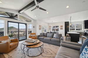 Living room with ceiling fan with notable chandelier, a mountain view, vaulted ceiling with beams, and recessed lighting