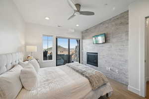 Bedroom with an accent wall, a large fireplace, visible vents, recessed lighting, and wood finished floors