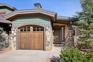 Property entrance with concrete driveway, stone siding, and a garage