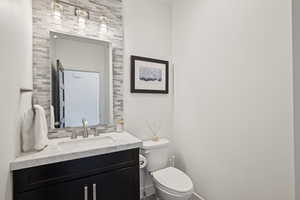 Bathroom with toilet, vanity, and baseboards