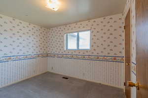 Carpeted spare room with visible vents, baseboards, and wallpapered walls