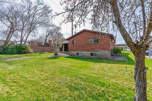 Rear view of property featuring a yard, fence, and brick siding