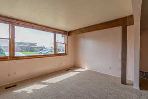 Spare room with visible vents, carpet floors, and a textured ceiling