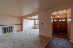 Entrance foyer featuring brick floor, a textured ceiling, baseboards, and a brick fireplace