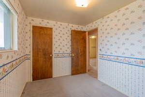 Carpeted empty room featuring wallpapered walls