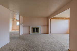 Unfurnished living room with a fireplace, carpet, and a textured ceiling