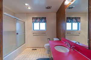 Bathroom with toilet, visible vents, and plenty of natural light