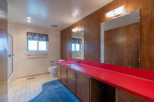 Full bath featuring an enclosed shower, visible vents, toilet, and vanity