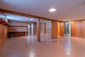 Finished basement with stairway, tile patterned floors, and wooden walls