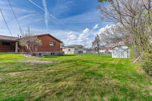 View of yard featuring a storage shed, fence, and an outdoor structure