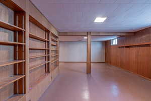 Below grade area with tile patterned floors, built in features, and wood walls