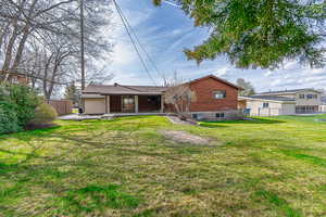 Rear view of house featuring a yard, brick siding, a patio area, and fence