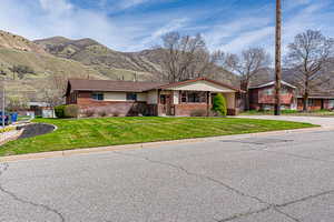 View of front facade featuring a mountain view, a front yard, and brick siding
