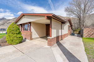View of front of home featuring concrete driveway, a mountain view, an attached carport, brick siding, and central AC