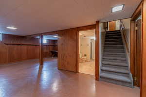 Basement featuring wood walls, tile patterned floors, and stairs