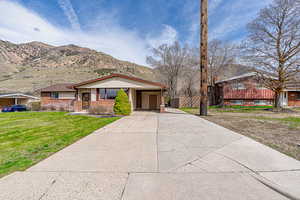 View of front of property featuring a carport, a mountain view, driveway, a front lawn, and brick siding