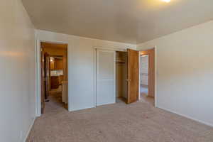 Unfurnished bedroom with a closet, baseboards, and light carpet
