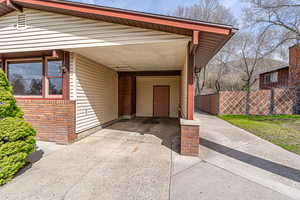 Exterior space with fence, an attached carport, and driveway